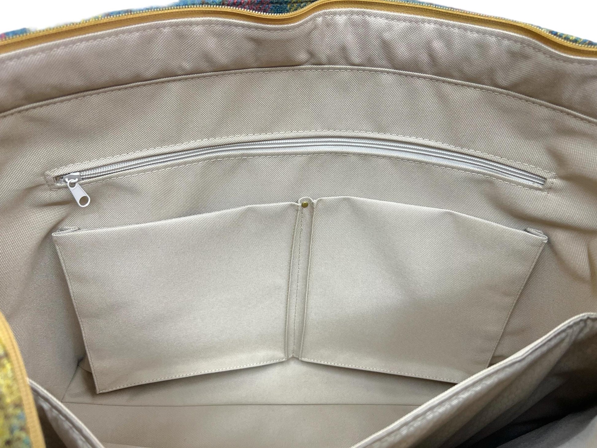 The interior is lined with khaki waterproof canvas. There is khaki waterproof hexagon ripstop inside of the pockets. The interior slip pockets of the tote are two large 3-D cargo pockets that are reinforced with rivets at the top corners as well as in the middle where the pockets are separated by stitching. There is also a long zippered pocket that is 6.5 inches deep and 18 inches long